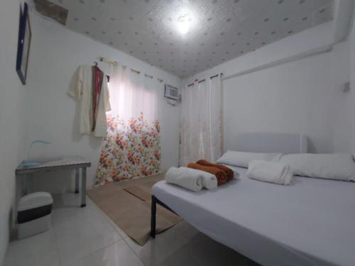 a white bedroom with a bed with towels on it at Eastdee AIRCON ROOM - RO1 in Biqui