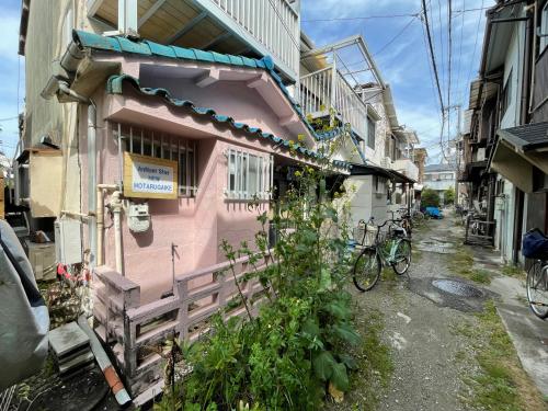 a pink house with a fence in front of it at AnNam Stay NEW HOTARUGAIKE in Toyonaka