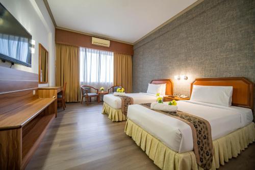 a hotel room with two beds and a television at Hotel Sandakan in Sandakan