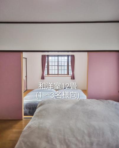 a bedroom with a large bed and a window at 民泊よこてこよ in Yokote