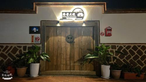a wooden door in a room with potted plants at 隆馨大悅古厝旅宿 in Jinhu
