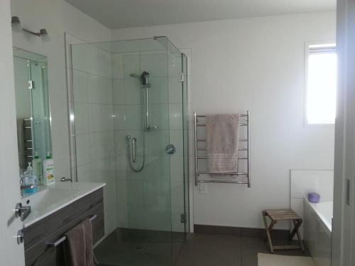 a bathroom with a glass shower and a sink at Cosy Mangawhai House in Mangawhai