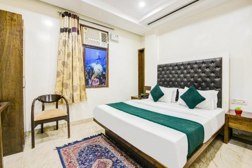 a bedroom with a bed and a chair and a window at Hotel Saffron Inn in New Delhi