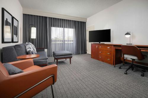 a hotel room with a couch and a television at Courtyard by Marriott Albuquerque Airport in Albuquerque