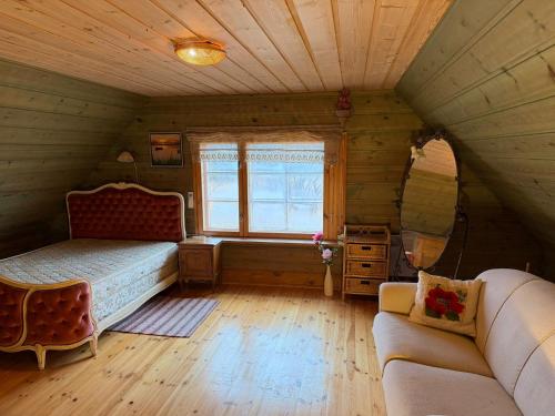 a room with a bed and a couch in a attic at Pitsinina Log House in Kaugatuma