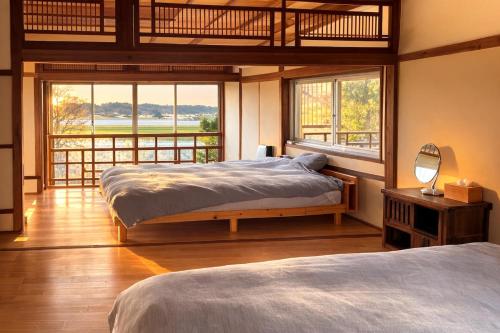 a bedroom with two beds and a large window at こちの宿 in Yamaga