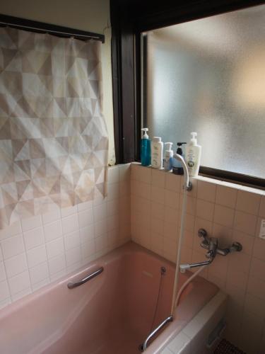 a bathroom with a pink tub and a window at The Asagiri Guest House in Tanabe