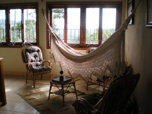 a hammock in a living room with a balcony at Refúgio do Azzi in Monte Verde