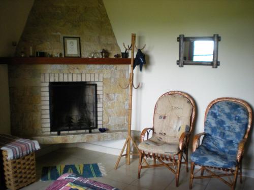 a living room with two chairs and a fireplace at Refúgio do Azzi in Monte Verde