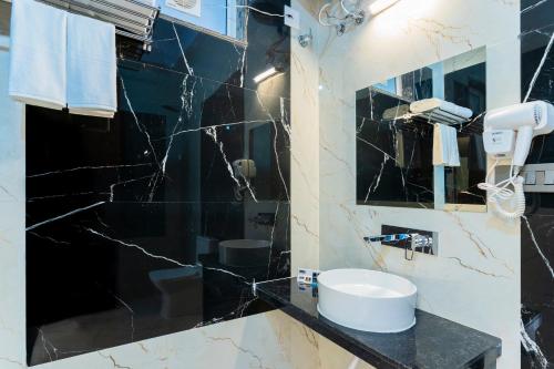 a black and white bathroom with a sink and a mirror at Kamdhenu - Luxurious stay in Udaipur