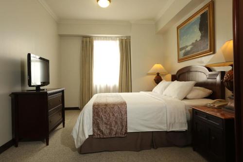 a hotel room with a bed and a television at Aryaduta Suite Semanggi in Jakarta