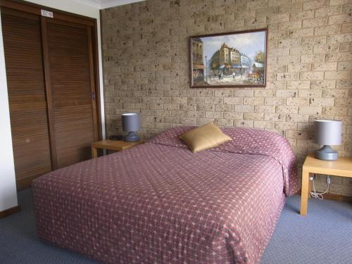 a bedroom with a bed with a purple comforter at A Furnished Townhouse in Goulburn in Goulburn