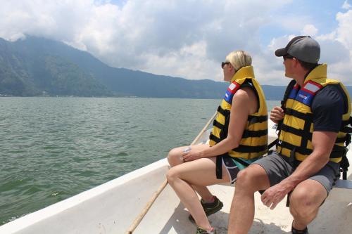 two people sitting on a boat in the water at Black Lava Hostel and Lodge in Kintamani