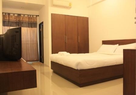 a bedroom with a bed and a flat screen tv at Sukontha Mansion in Ban Khlong Naraphirom