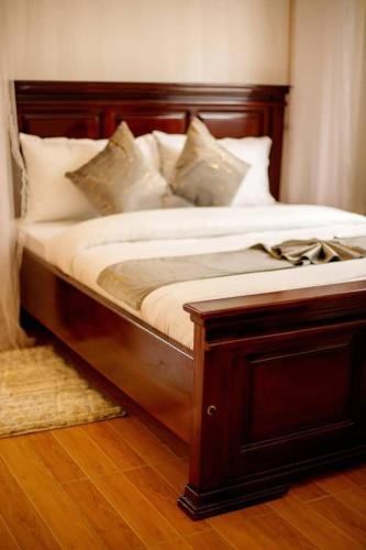 a bed with a wooden frame and pillows on it at Pakihotels&apartment in Moshi