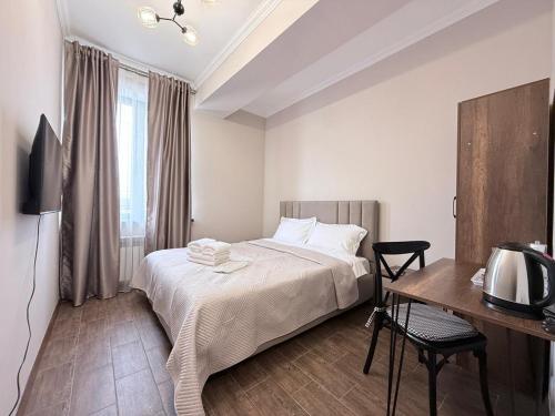 a bedroom with a bed and a desk and a television at Orion Hotel in Almaty