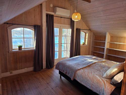 a bedroom with wooden walls and a bed with windows at Norra Vilan - Hagalund in Kopparberg