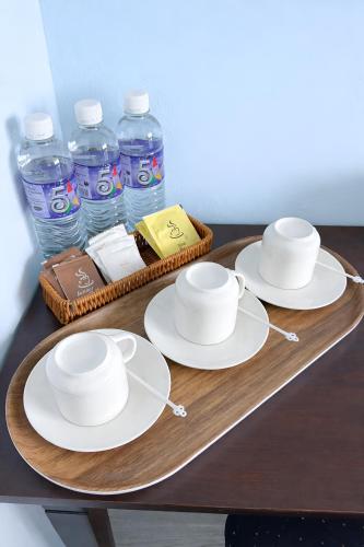 two cups and plates on a tray with bottles of water at Neela House in Labuan