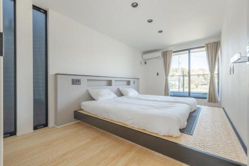 a white bedroom with a large bed and a window at Charm Roger Luxury Room 2 in Kamakura