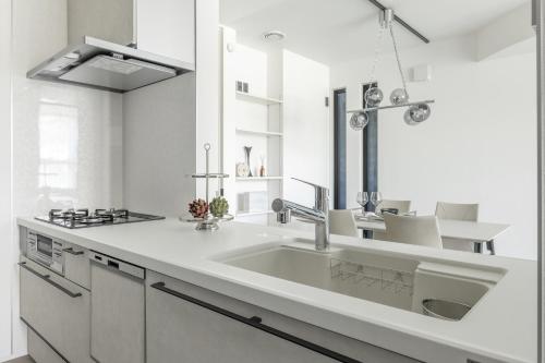 a white kitchen with a sink and a stove at Charm Roger Luxury Room 2 in Kamakura