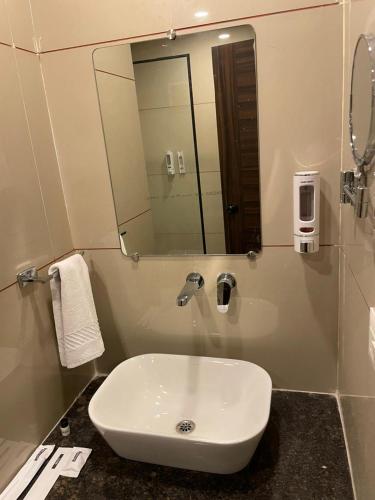 a white sink in a bathroom with a mirror at Hotel Mahavir in Ankleshwar