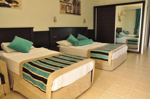 a bedroom with two beds and a mirror at Kleopatra Royal Palm Hotel in Alanya