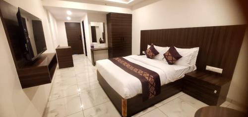 a bedroom with a bed and a flat screen tv at Hotel Mahavir in Ankleshwar