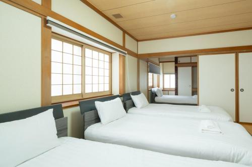 two beds in a room with windows at Asahikawa Kawabata House in Asahikawa