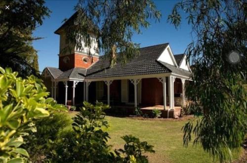 a house with a clock tower on top of it at Ithaca 1896 Manor in Busselton