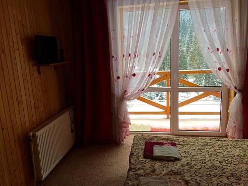 a bedroom with a large window and a bed with a blanket at Dream House in Yablunytsya