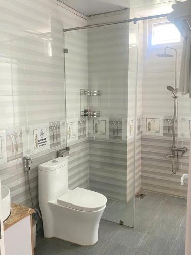 a white bathroom with a toilet and a shower at HP Truong Hotel Phu Quoc in Phú Quốc