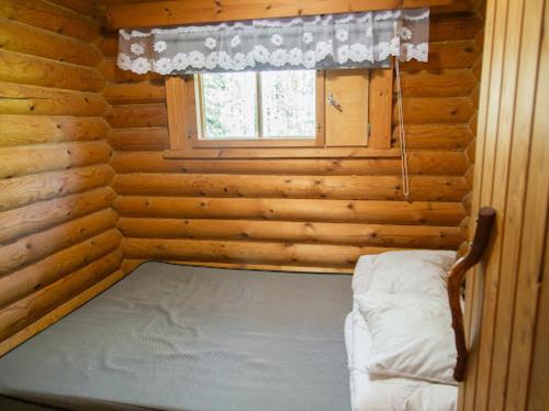 a bed in a log cabin with a window at Juhantupa in Keuruu