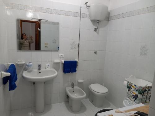 a woman taking a picture of a bathroom with a toilet and sink at Appartamento L'Orchidea in Forio d'Ischia