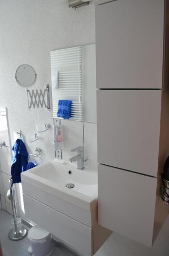 a white bathroom with a sink and a mirror at Die Dirndlkönigin in Grünenbach