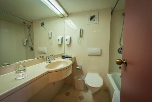 uma casa de banho com um lavatório, um WC e um espelho. em Shalom Jerusalem Hotel em Jerusalém