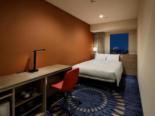 a hotel room with a bed and a desk with a red chair at Sunshine City Prince Hotel Ikebukuro Tokyo in Tokyo