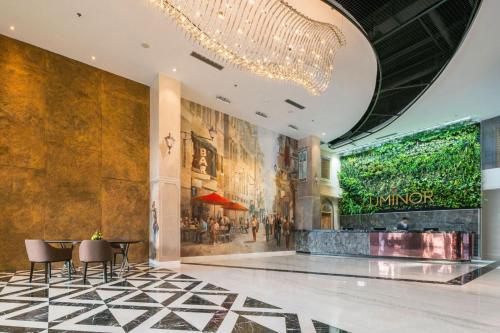 a lobby with a chandelier and a table and chairs at Luminor Hotel Pecenongan Jakarta By WH in Jakarta