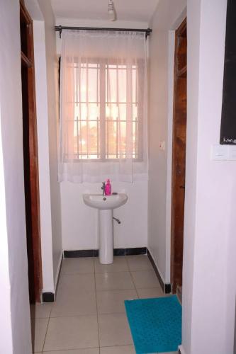 a white bathroom with a sink and a window at Gessy Homes in Eldoret