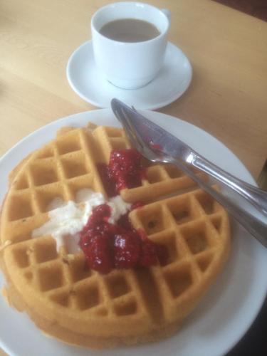 a plate of waffles with berries and a cup of coffee at Sunne Hembygdsgård B&B in Sunne