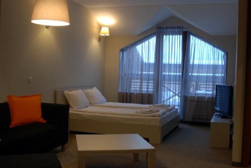 a room with a bed and a couch and a tv at White Lavina - Ski, Bike, Hike in Bansko