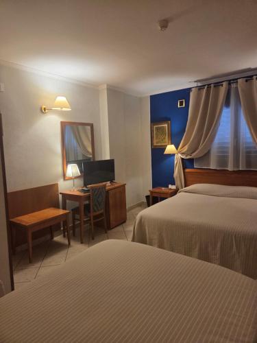 a hotel room with two beds and a desk with a computer at Hotel Ristorante Rinelli in Margherita di Savoia