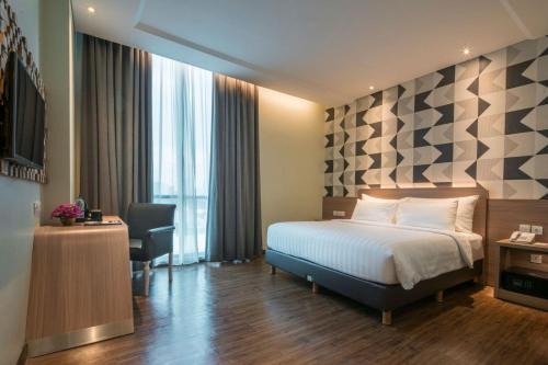 a hotel room with a bed and a desk at Luminor Hotel Pecenongan Jakarta By WH in Jakarta