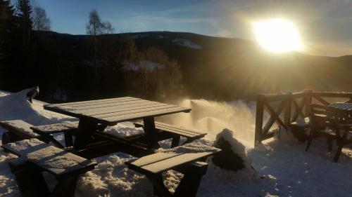 a picnic table in the snow with the sun behind it at Penzion Alenka in Špindlerův Mlýn