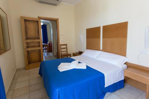 a hotel room with a bed with a blue blanket at Hotel Resort Portoselvaggio in Sant'Isidoro