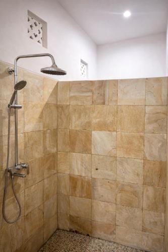 a shower with a shower head in a bathroom at The Kubu Sidemen in Silebeng