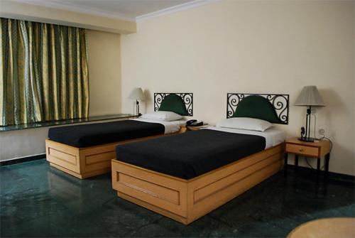two beds in a hotel room with sidx sidx sidx sidx at The Hotel Airport in Vadodara