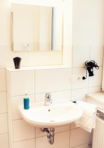 a white bathroom with a sink and a mirror at Hotel - Stadtvilla Central in Schweinfurt