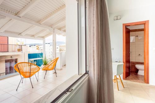 a room with a balcony with chairs and a bathroom at Coral Hotel - Hotelia Hospitality Group in Ierapetra