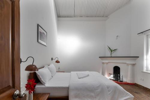 a white bedroom with a bed and a fireplace at Hideaway Art Residency in Ooty
