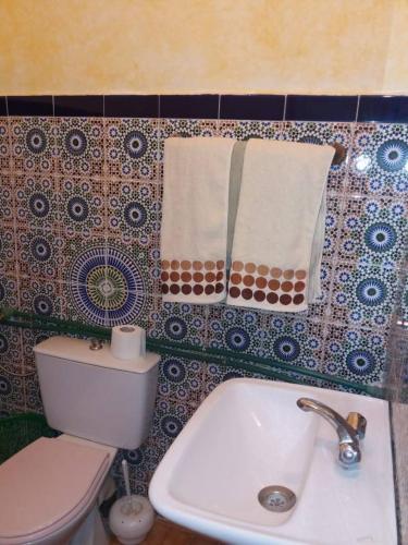a bathroom with a toilet and a sink and towels at Chez Moulay Ismail in Agdz